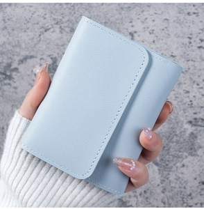Macro detail of light blue leather wallet showing pebbled texture and fine stitching