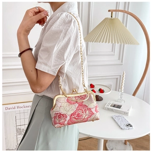 Detailed view of a pink floral embroidered qipao handbag with gold metal frame and chain strap