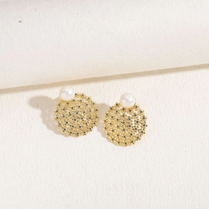 Close-up of gold earrings with pearl and blue stones in a hollow floral design