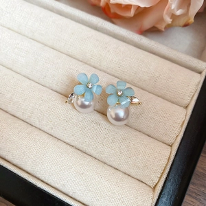 Detailed macro view of light blue flower pearl studs with rhinestones and golden base