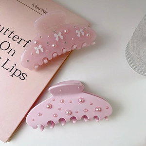 Pink bow hair claw clips with rhinestones and pearls on a stylish aesthetic background