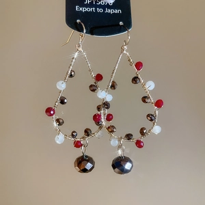 Detail of handmade gold wire teardrop earrings with red and white crystal beads
