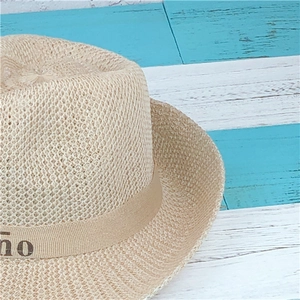 Detail of woven straw fedora with decorative beige ribbon on rustic wood background
