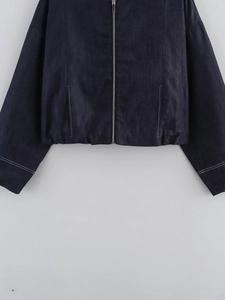 Detail of dark blue denim jacket showing metal zipper and white contrast stitching