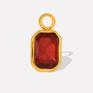 Detailed macro view of a gold-plated geometric pendant with a red rectangular gemstone