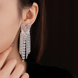 Close-up of dangling heart earrings with sparkling pink rhinestones and elegant tassels