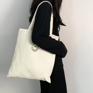 Close-up of cream canvas tote bag with black line smiley face print for daily school use