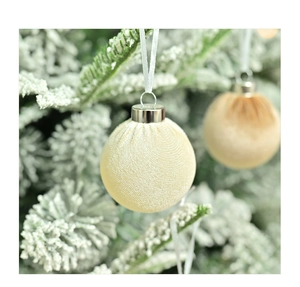 Detail of champagne velvet Christmas ball ornament with thread texture on snowy branch