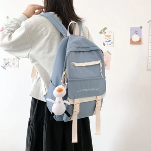 Detail of blue school backpack with duck charm and Chen Hao print on back of student