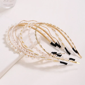 Detail of golden metal headbands with elegant white faux pearls on white background