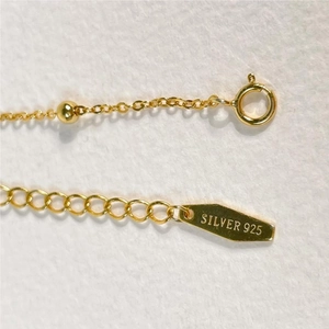 Macro detail of gold-plated S925 sterling silver chain with lobster clasp and hallmark tag