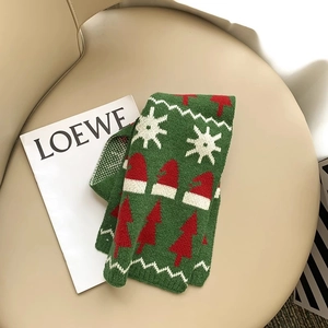 Close-up of green knitted scarf with Christmas tree and snowflake patterns on beige leather