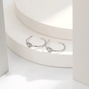 Macro shot of silver evil eye earrings with white opal center on minimalist stands
