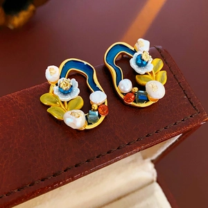 Macro shot of vintage gold flower earrings with blue enamel and pearls on leather box