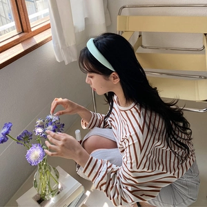 Woman wearing a mint green wide headband in a refreshing lifestyle setting with flowers