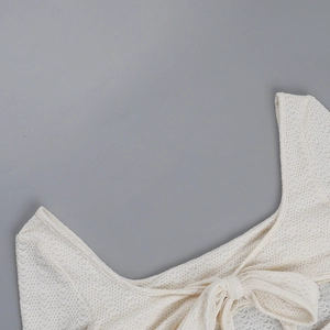 Détail d'un haut en dentelle blanche avec décolleté carré et nœud papillon élégant