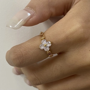 Detail of a gold stainless steel clover ring with zircon stones worn on finger