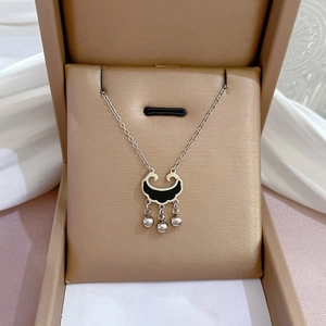 Detailed view of silver Ruyi lock pendant with black inlay and bells in a jewelry box