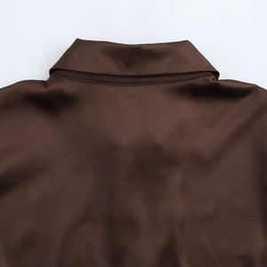 Gros plan détaillé du col d'un haut en satin marron foncé avec texture de tissu brillant