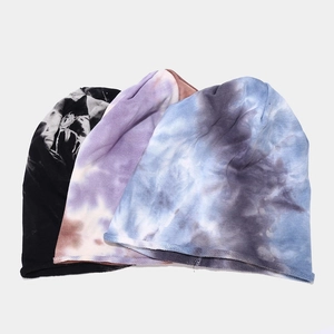 Three trendy tie-dye knitted slouchy beanies in black, purple and blue displayed flat