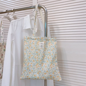 Detail of floral tote bag with cream velvet texture and minimalist square fabric label