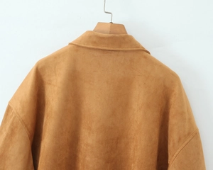 Detail of the upper back and shoulder of a brown suede jacket against a white wall