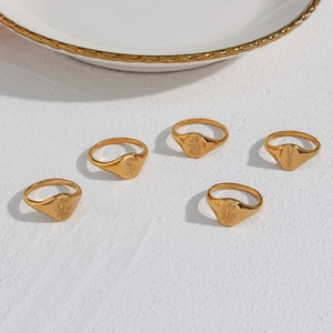 Close-up of five gold stainless steel signet rings with delicate floral engravings