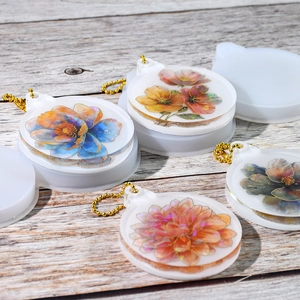 Makroaufnahme von Blumen-Resin-Anhängern mit goldenen Kugelketten auf Holzgrund