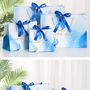 Detail of blue marble paper gift bags with dark blue ribbon handles and gold HAPPY TIMES logo