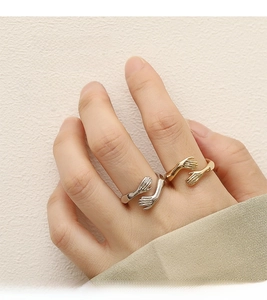 Detail of silver and gold hug rings on fingers showing minimalist open palm design