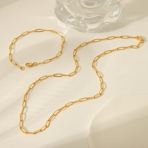 Golden paperclip chain necklace and bracelet set displayed on a white minimalist background
