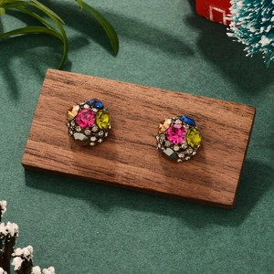 Macro d'oreilles boules aux strass colorés présentées sur un support en bois chic