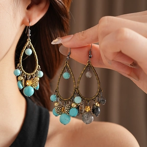 Detailed close-up of retro bronze earrings with teal beads and bamboo leaf metallic design