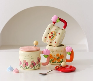 Detail of tulip ceramic mug with floral pattern and flower-shaped handle on white desk