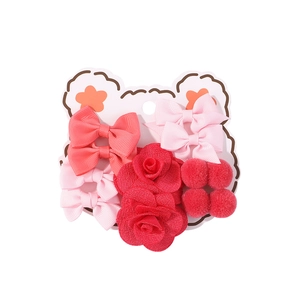 Dettaglio del set di accessori per capelli con fiocchi rosa e pon-pon rossi per bambini