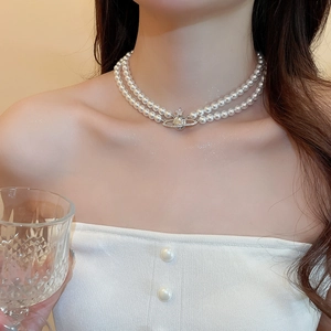 Close-up of double-layer pearl necklace with a shimmering zircon Saturn planet pendant