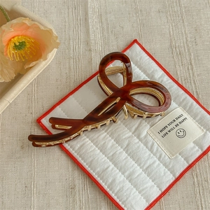 Detailed close-up of brown tortoise shell pattern and hollow bow metal hair claw clip