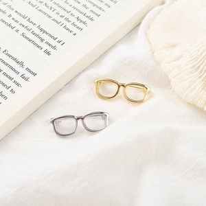 Macro view of gold and silver metal glasses pins on soft fabric background