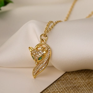 Elegant gold fox pendant necklace with green crystal eyes on luxurious white silk