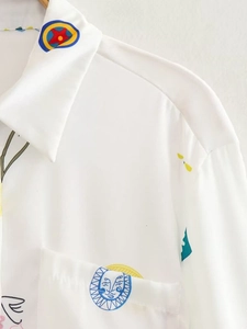Détail du col rabattu et de l'imprimé abstrait coloré sur une chemise blanche décontractée