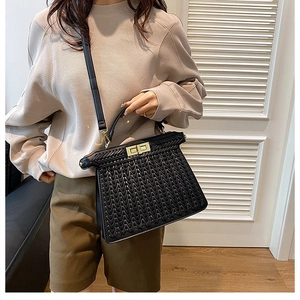 Detail of black woven handbag showing gold hardware lock and detachable shoulder strap