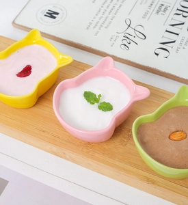 Detailed view of cat-shaped ceramic sauce bowls in yellow, pink and green colors