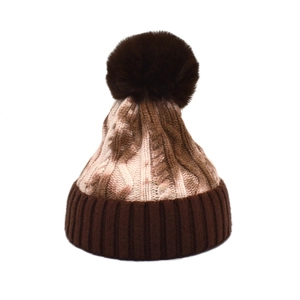Detail of winter tie-dye knit beanie with large pom-pom and thick ribbed cuff texture