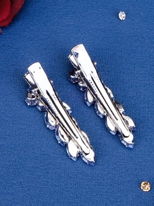 Detailed view of silver alloy leaf hair clips with clear crystals on blue background