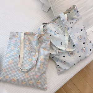Detail von zwei blauen Baumwolltaschen mit Bärenmotiven und cremeweißen Trägern