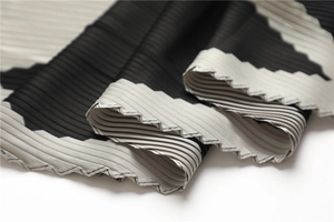 Close-up of black and grey pleated silk scarf showing vertical texture and fine edge stitching