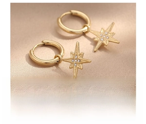 Detailed view of gold starburst earrings with crystals on champagne silk background