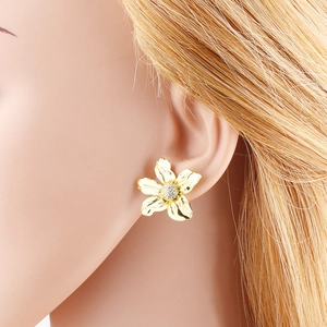 Pendientes de flores doradas con circonitas microincrustadas en una modelo