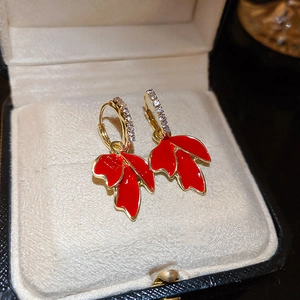 Détails de boucles d'oreilles feuille d'érable dorées avec émail rouge et pierres de zircon