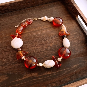 Detailed view of amber and cream acrylic beads on a wooden tray with golden spacers
